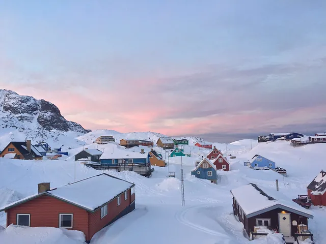 An Artic landscape with cabins of different primary colors consisting of yellow, blue, red, and green, the sky is peach falling into silver gray blue.
